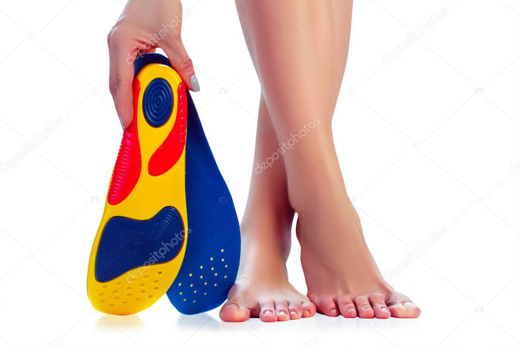 orthopedic insole in the hand and female feet stand on tiptoe