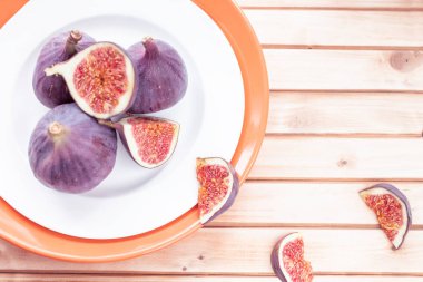 incir ahşap çizgili arka plan üzerinde turuncu bir kase dilimlenmiş