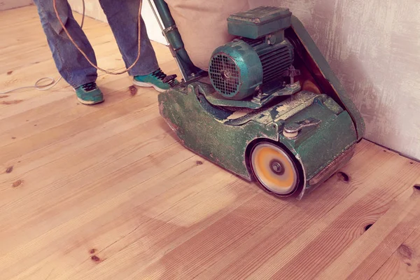 Tischler arbeitet mit elektrischer Holzschleifmaschine in einem Raum — Stockfoto
