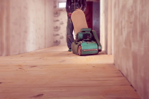 Tischler arbeitet mit elektrischer Holzschleifmaschine in einem Raum — Stockfoto