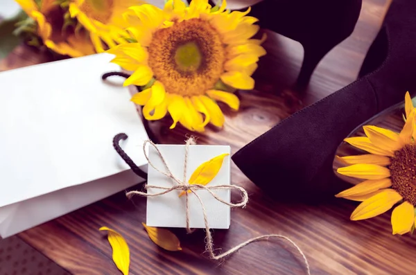 Geschenk, gelbe Sonnenblumen und schwarze Schuhe — Stockfoto