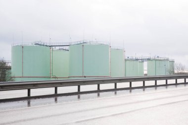 Büyük silindirik petrol konteyner kırmızı ayrıntıları içeren bir yolun kenarında