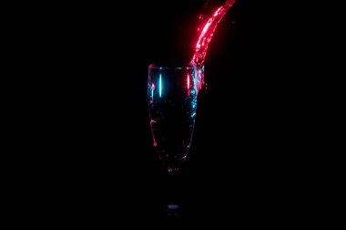 Siyah bir arka plan üzerinde izole bir bardak içine dökme parlak kırmızı su akışı