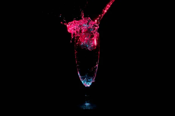Rosso acqua evidenziata schizzi di vetro champagne isolato su uno sfondo nero Immagine Stock