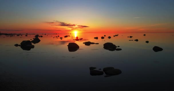 一个充满红色的日落的时间流逝 云层在平静的海面上移动 点缀着巨石 — 图库视频影像