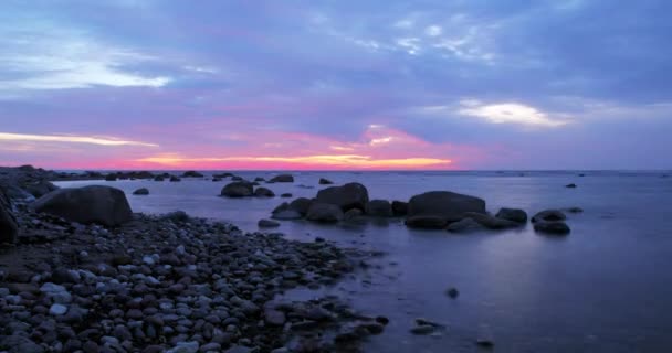 岩の多い海岸の上の青い雲の背後にある黄金の夕日の時間経過 — ストック動画