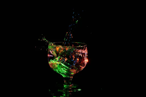 Yeşil bir süslü cam sıçramasına ışık altında sıvı — Stok fotoğraf