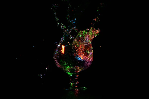 Multicolored splash of water in glass isolated on black — Stock Photo, Image