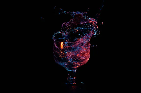 Вода в ярких красках, выплескивающаяся из стекла — стоковое фото