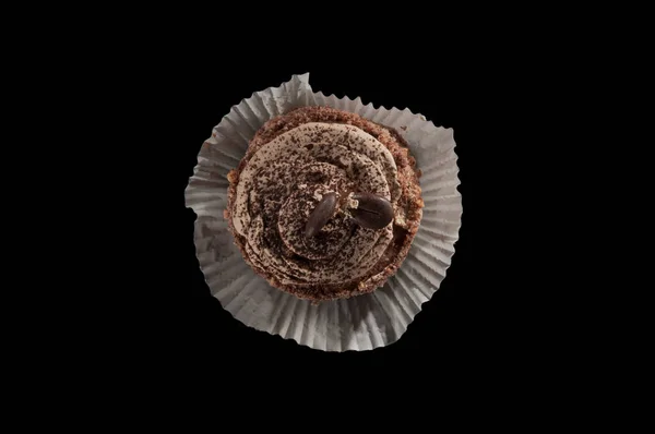 Top view of small desert with frosting and coffee beans isolated on a black background