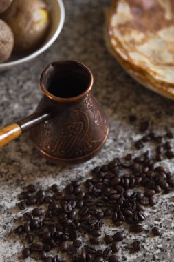 Cezve kahve çekirdekleri ve arka planda haşlanmış patates ile pancakes ile