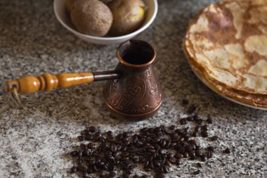 Cezve kahve çekirdekleri ve arka planda haşlanmış patates ile pancakes ile