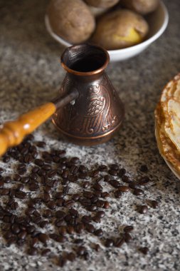 Cezve kahve çekirdekleri ve arka planda haşlanmış patates ile pancakes ile