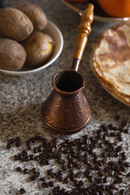 Cezve kahve çekirdekleri ve arka planda haşlanmış patates ile pancakes ile