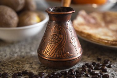 Cezve kahve çekirdekleri ve arka planda haşlanmış patates ile pancakes ile