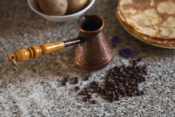 Cezve kahve çekirdekleri ve arka planda haşlanmış patates ile pancakes ile