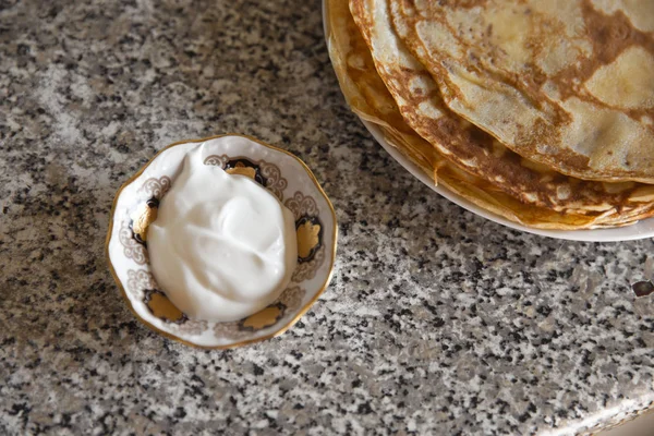 Lívance se zakysanou smetanou na kithcen stůl a porcelánové soška kočka — Stock fotografie