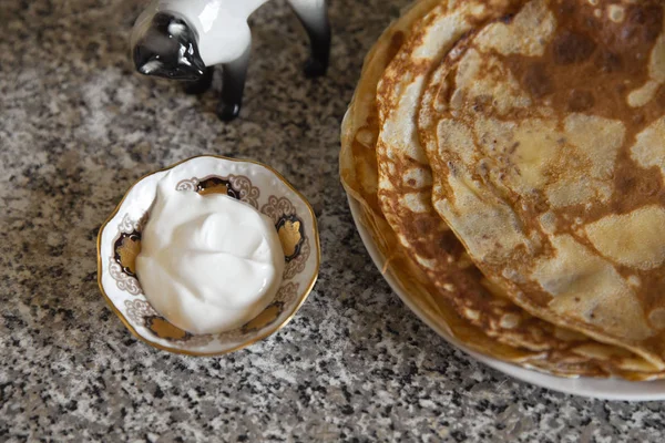 Lívance se zakysanou smetanou na kithcen stůl a porcelánové soška kočka — Stock fotografie