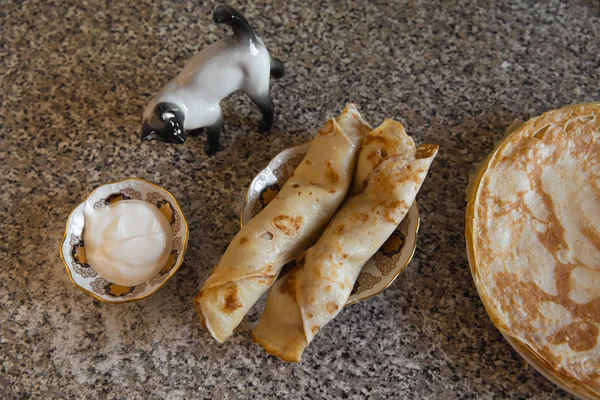 Palacsinta, konyha asztal és egy macska porcelán szobor tejföllel — Stock Fotó