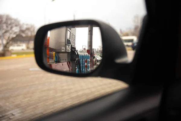 A rear window in a side car mirror during a break stop at a gas station