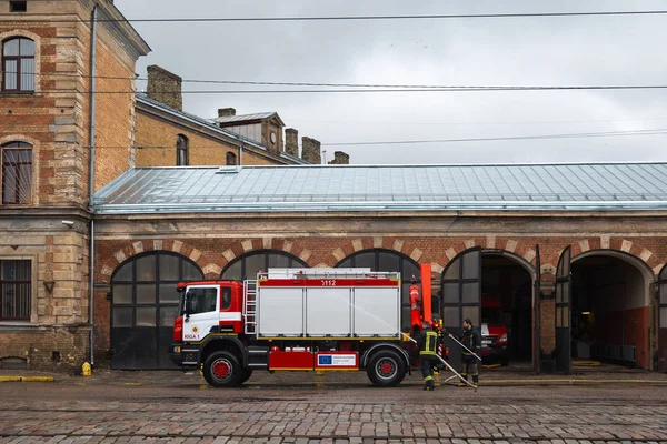 РИГА, Латвия - 16 марта 2019 года: Пожарная машина очищается - водитель моет пожарную машину в депо — стоковое фото