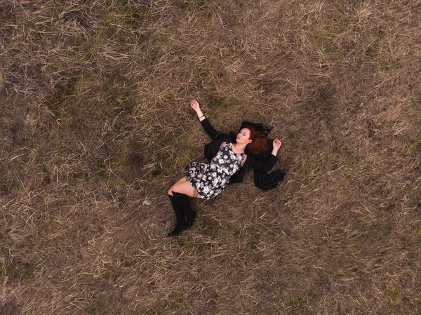 Vista superior de un avión no tripulado aéreo de una chica acostada en un campo relajante y bailando. Usar un vestido con medias —  Fotos de Stock