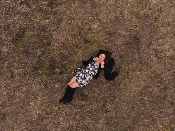 Vista superior de un avión no tripulado aéreo de una chica acostada en un campo relajante y bailando. Usar un vestido con medias —  Fotos de Stock
