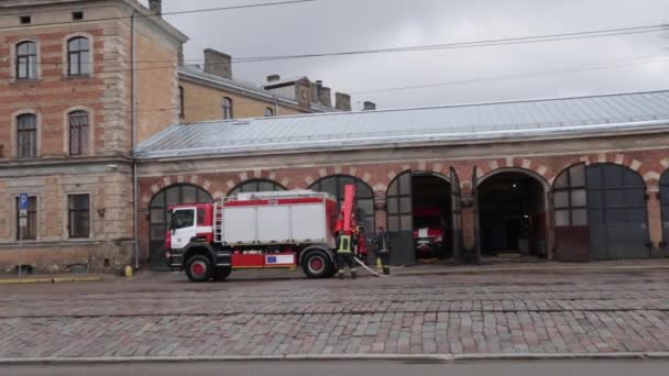 РИГА, ЛАТВИЯ - 16 марта 2019 года: Пожарная машина очищается - водитель моет пожарную машину в депо - Сценический вид — стоковое видео