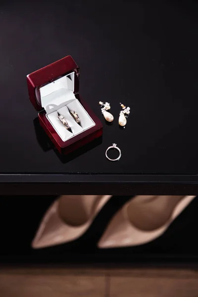 Brudkläder Detaljer - vigselringar medan bruden redo innan ceremonin - örhängen och skor med klack är bokeh — Stockfoto