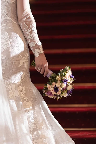 Bröllop bukett i en hand av en brud med röda trappor i bakgrunden — Stockfoto
