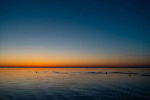 Vivid increíble puesta de sol en los Estados Bálticos - Atardecer en el mar con horizonte se ilumina por el sol — Foto de Stock