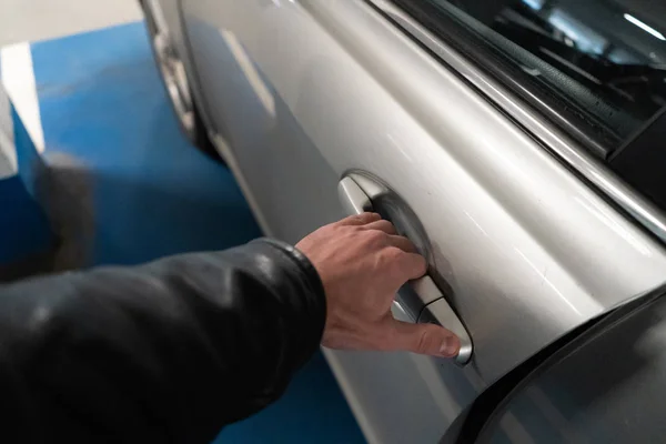 Feche uma mão dos homens na trava de uma porta do carro abrindo-o - carro de cor clara — Fotografia de Stock