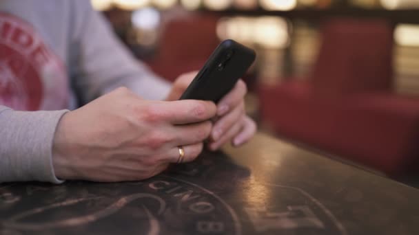 Un jeune homme d'affaires assis à une table dans un café à l'aide d'un iphone et de textos dactylographier un message - Les gens qui réussissent, la routine quotidienne 