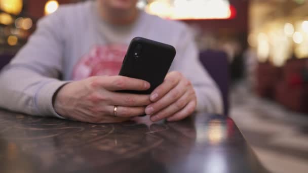 Un jeune homme d'affaires assis à une table dans un café à l'aide d'un iphone et de textos dactylographier un message - Les gens qui réussissent, la routine quotidienne 