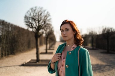 Genç moda sevgilisi kadın canlı yeşil ceket ve renkli bir etek giyen bir parkta Waling