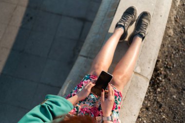 Genç bir kadına genel bakış bir çeşme üzerinde oturan bir saray parkında telefon kullanır-yukarıdaki görünüm