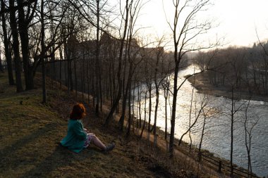 Genç moda kadın rahatlatıcı ve Bauska bir nehir yakınında günbatımı zevk, Letonya, 2019