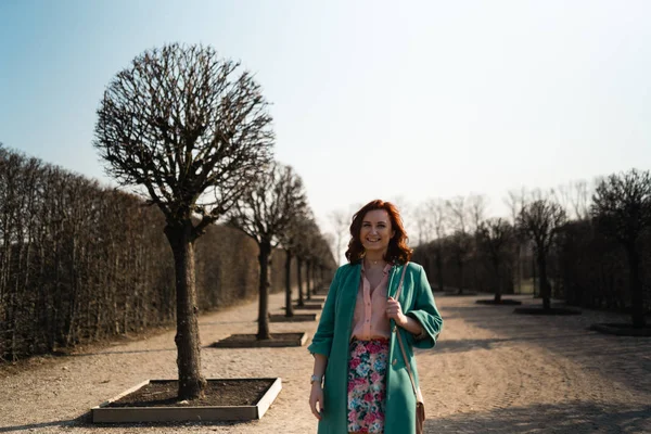 Jovem amante da moda mulher waling em um parque vestindo jaqueta verde vívida e uma saia colorida — Fotografia de Stock