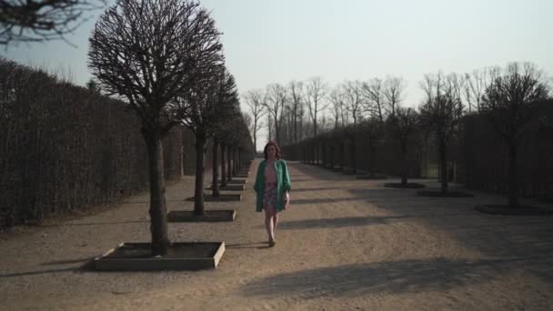 Mode liebende junge Frau spaziert im Frühling im Park - nackte Bäume im rundale Park - glückliches Mädchen bei sonnigem Wetter — Stockvideo