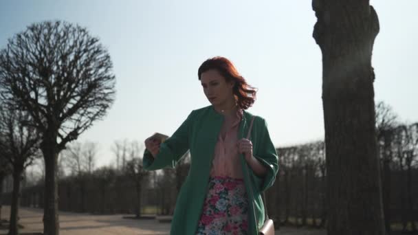 Young girl taking phone out of pocket and texts a message wearing green fashion jacket and colorful skirt — Stock Video