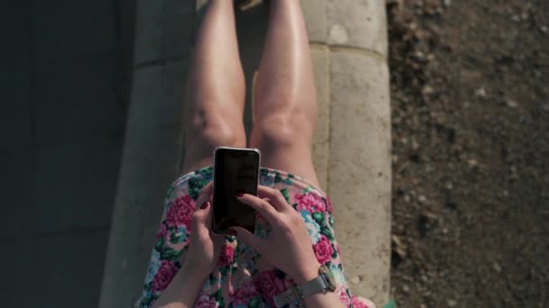 Detalj närbild sköt av en mode beroende ung kvinna som använder sin telefon-textning och meddelanden-bär grön jacka och en färgglad levande kjol — Stockvideo