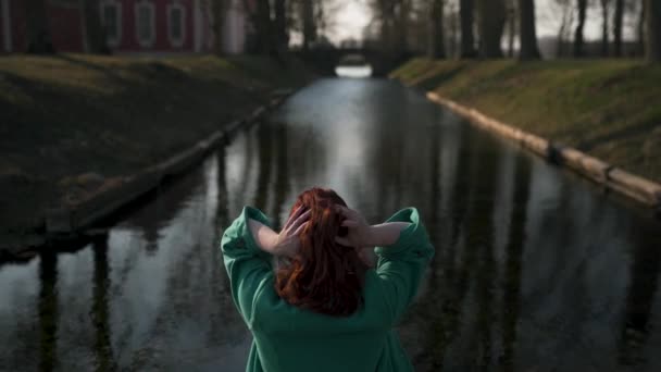 Mladá žena, která odpočívne nedaleko od paláce v paláci v teplém jarním počasí na zeleném kabátě-Redhead — Stock video
