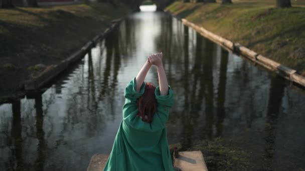 Giovane donna che si rilassa vicino a un canale parte palazzo durante un caldo clima primaverile indossando giacca di moda verde - Rossa — Video Stock