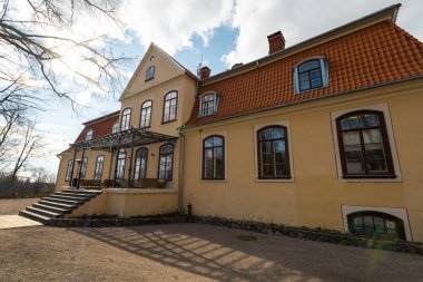 Liepupe, Letonya-13 Nisan 2019: mavi gökyüzü ve bulutlar ile güzel güneşli bahar havalarda Liepupes Muiza malikanesi