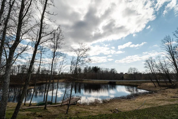 Liepupe, Lettland-april 13, 2019: Liepupes Muiza herrgård i härligt soligt fjädra väder med blått Sky och moln-laken parkerar med avspeglar ytbehandlar — Stockfoto