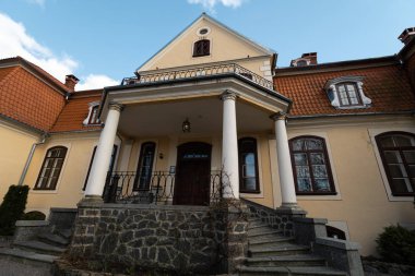 Liepupe, Letonya-13 Nisan 2019: mavi gökyüzü ve bulutlar ile güzel güneşli bahar havalarda Liepupes Muiza malikanesi