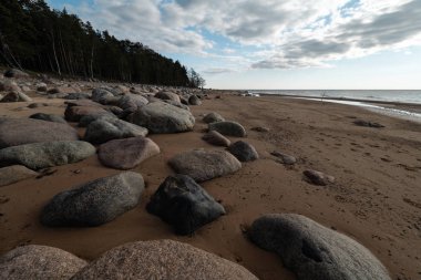 Veczemju Klintis-Nisan 2019 Baltık ülkesinde Letonya Boulder plaj-donuk bulutlar ve güneş biraz bulutlu gökyüzü