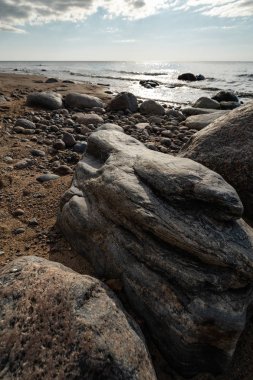 Veczemju Klintis-Nisan 2019 Baltık ülkesinde Letonya Boulder plaj-donuk bulutlar ve güneş biraz bulutlu gökyüzü