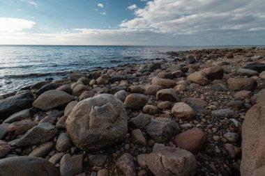 Veczemju Klintis-Nisan 2019 Baltık ülkesinde Letonya Boulder plaj-donuk bulutlar ve güneş biraz bulutlu gökyüzü