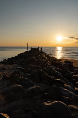Baltık Denizi 'nde canlı kırmızı ve turuncu renklerle Boulder plaj İskelesi günbatımı-Tuja, Letonya-13 Nisan, 2019